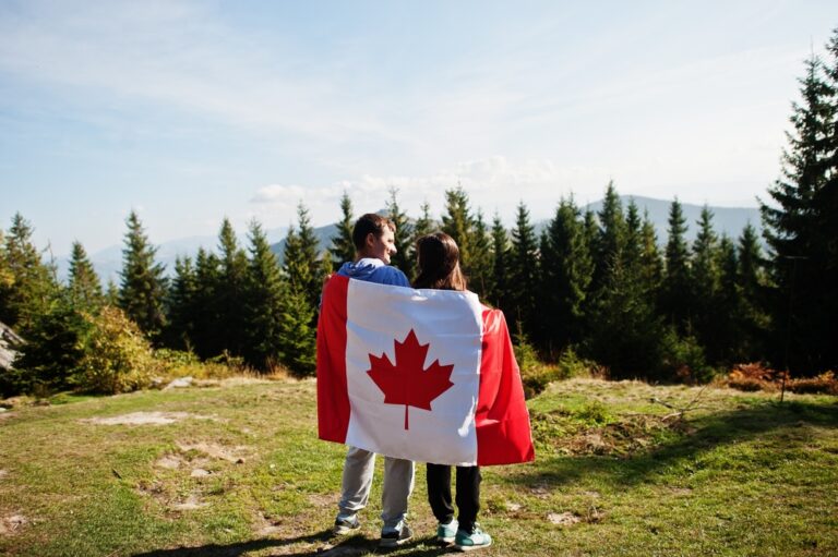 Happy,Canada,Day.,Couple,With,Large,Canadian,Flag,Celebration,In